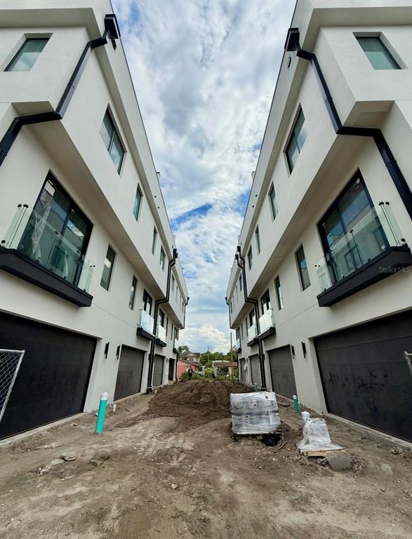 An exterior view shows two modern, multi-story townhomes facing each other across a dirt driveway — 310 W COLUMBUS DRIVE UNIT 7, TAMPA, FL