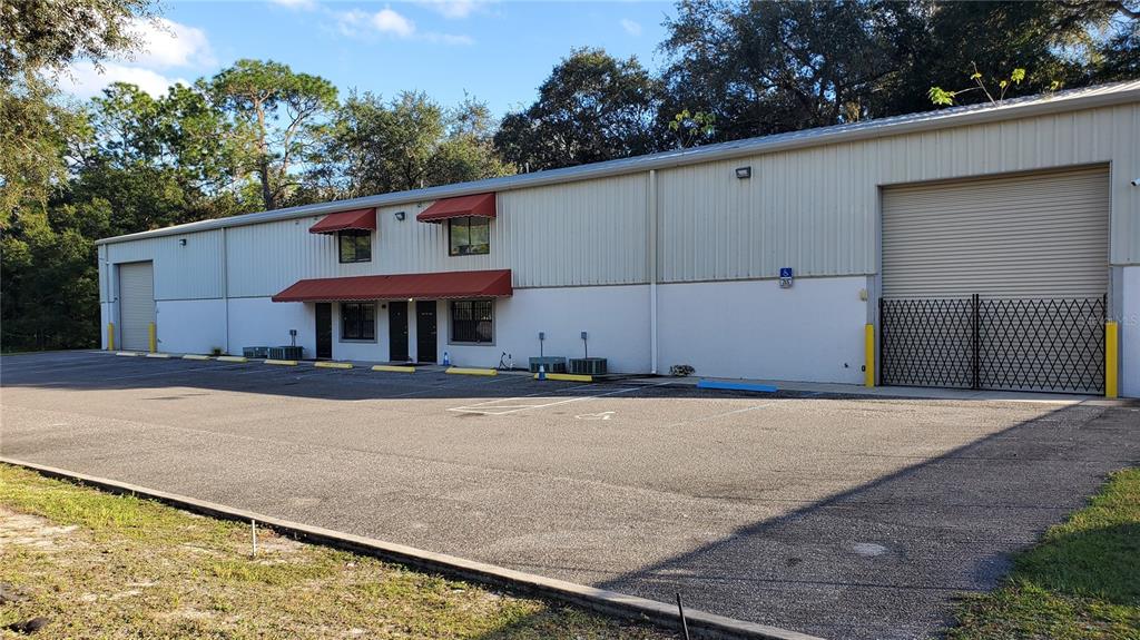 A single-story industrial building with a metal exterior, red awnings, and a paved parking lot — 3720 NE 47TH PLACE, OCALA, FL