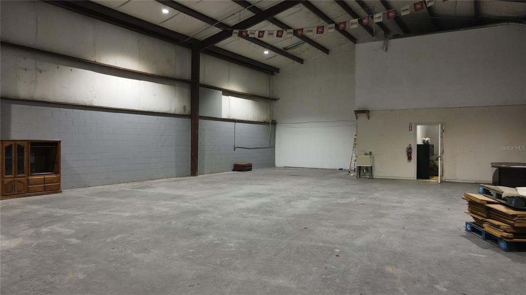 A large, open warehouse space features concrete floors, block walls, and exposed ceiling rafters — 3720 NE 47TH PLACE, OCALA, FL