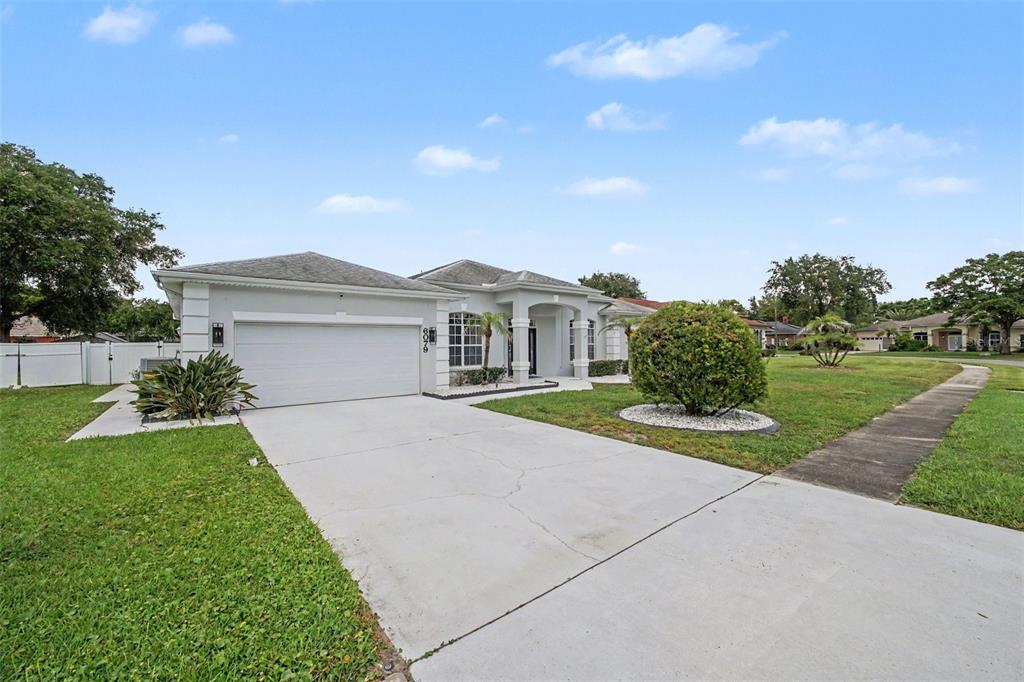 A single-story house with a white garage, a concrete driveway, and a manicured front lawn — 6079 RED STAG DRIVE, PORT ORANGE, FL
