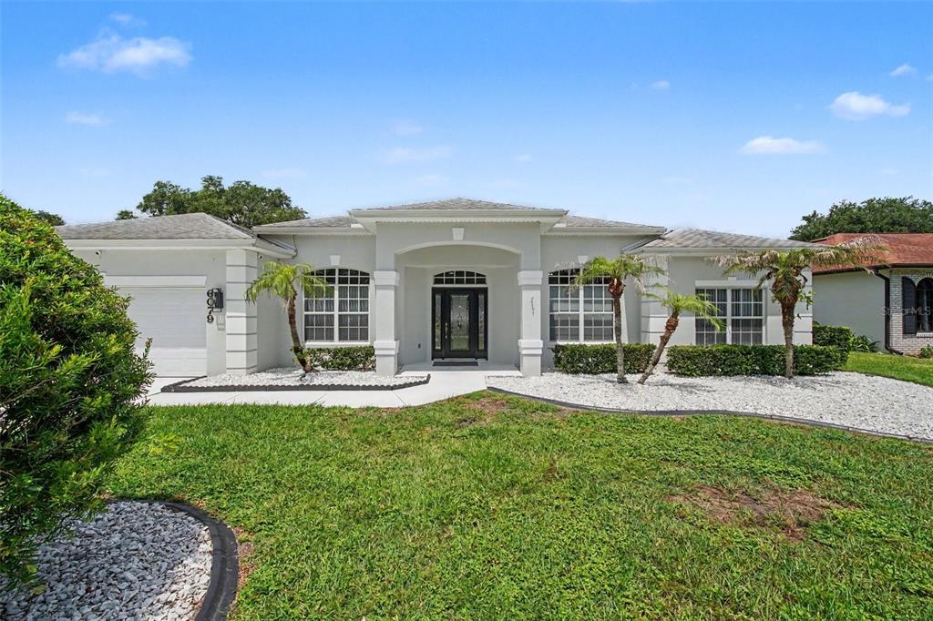 A single-story house with a light-colored stucco exterior, a front porch, and a garage — 6079 RED STAG DRIVE, PORT ORANGE, FL
