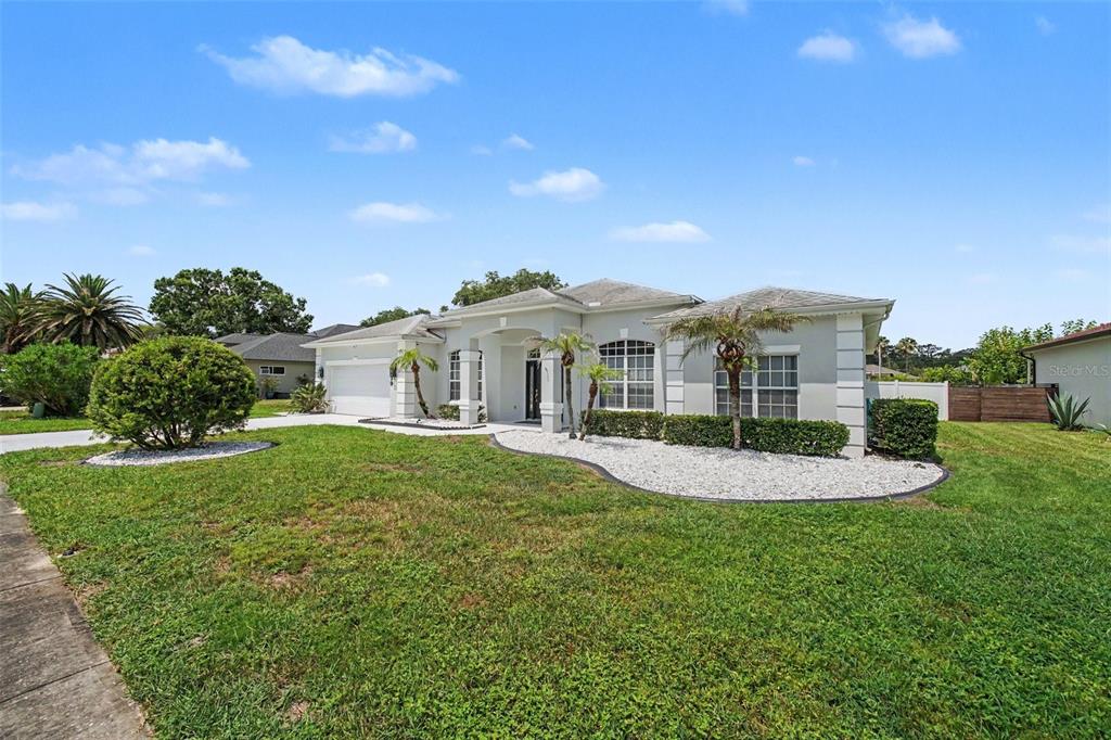 A single-story house with a white stucco exterior, a two-car garage, and a landscaped yard — 6079 RED STAG DRIVE, PORT ORANGE, FL