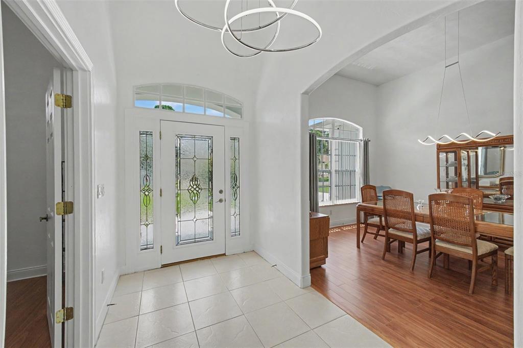 A bright entryway with tiled floors leads into a dining room with wood flooring — 6079 RED STAG DRIVE, PORT ORANGE, FL