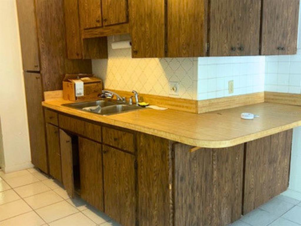 A kitchen features wood cabinets, a double-basin sink, and a light-colored laminate countertop — 208 13TH STREET SW, LARGO, FL