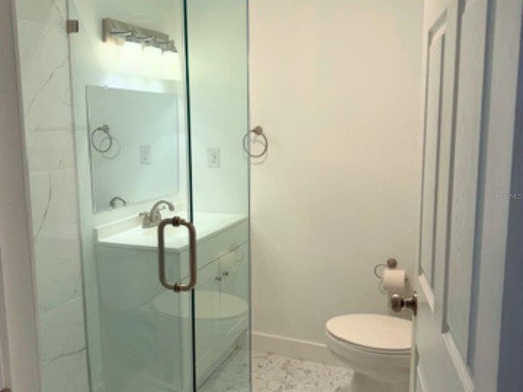 A bathroom features a glass-enclosed shower, a white vanity with a mirror, and a toilet — 208 13TH STREET SW, LARGO, FL