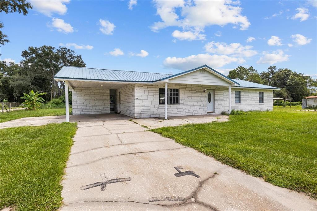 A single-story house with a white stone facade, a metal roof, and an attached carport — 9545 STATE ROAD 33 N, POLK CITY, FL