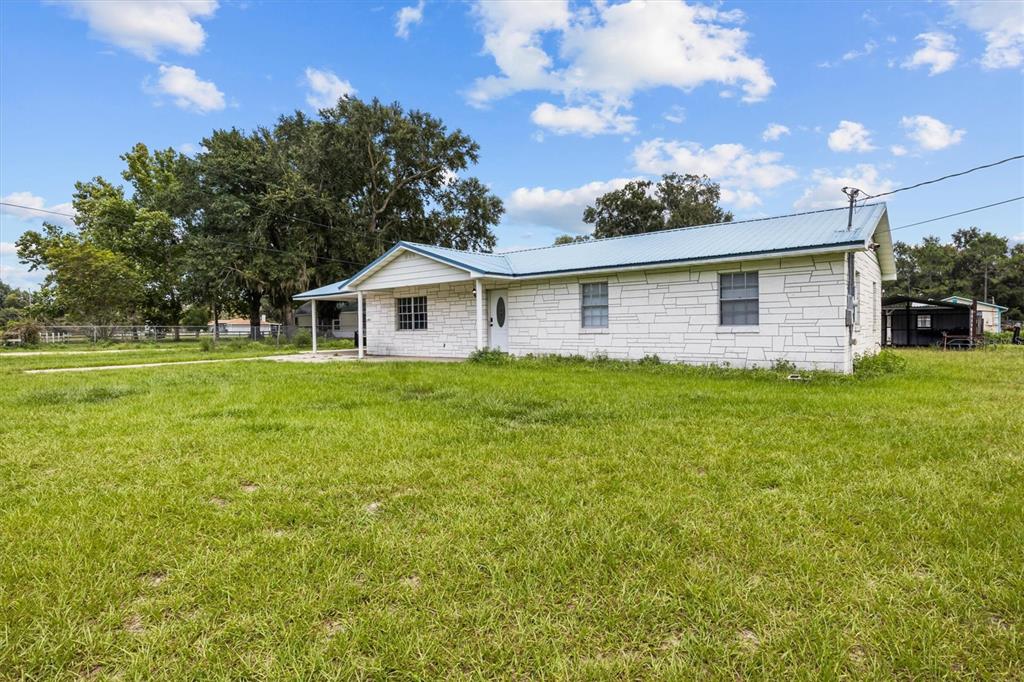 A single-story house with white stone siding and a light blue metal roof — 9545 STATE ROAD 33 N, POLK CITY, FL