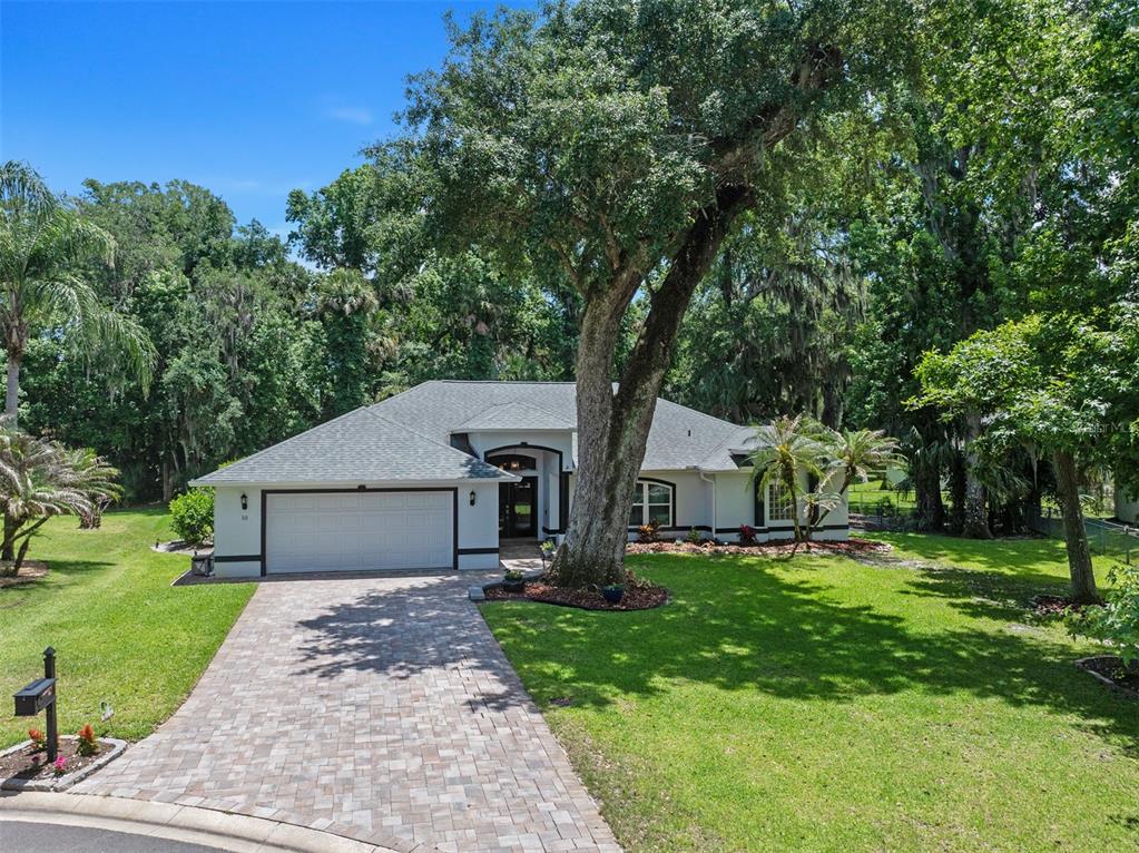 A single-story house with a white exterior, dark trim, and a paver driveway — 10 COTTON MILL COURT, ORMOND BEACH, FL