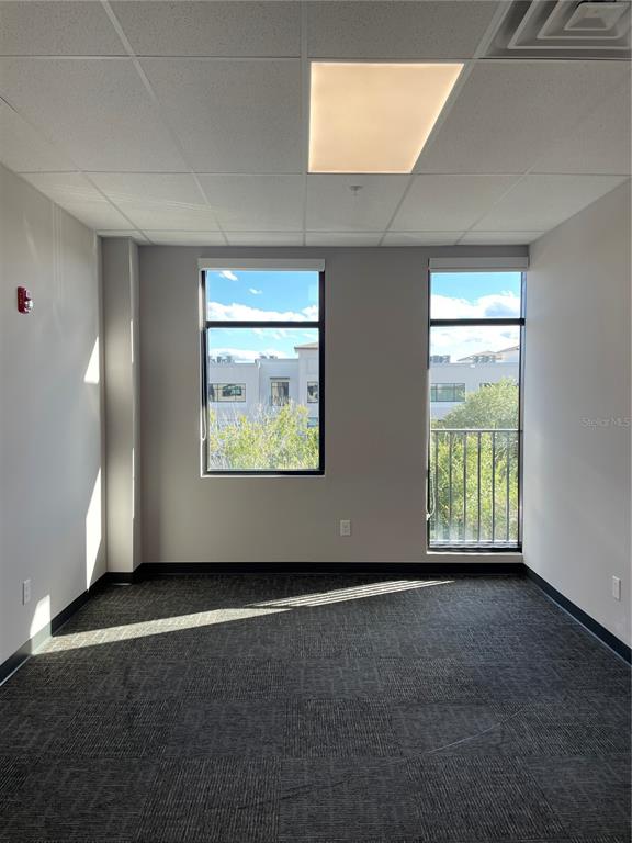 An empty office space features gray carpet, light-colored walls, two windows, and a drop ceiling — 13550 VILLAGE PARK DRIVE UNIT 345, ORLANDO, FL