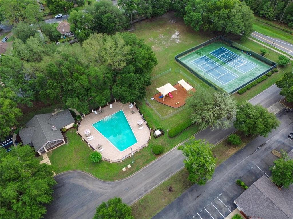 An aerial view shows a swimming pool, a playground, and tennis courts near a building — 3758 NW 56TH LANE, GAINESVILLE, FL