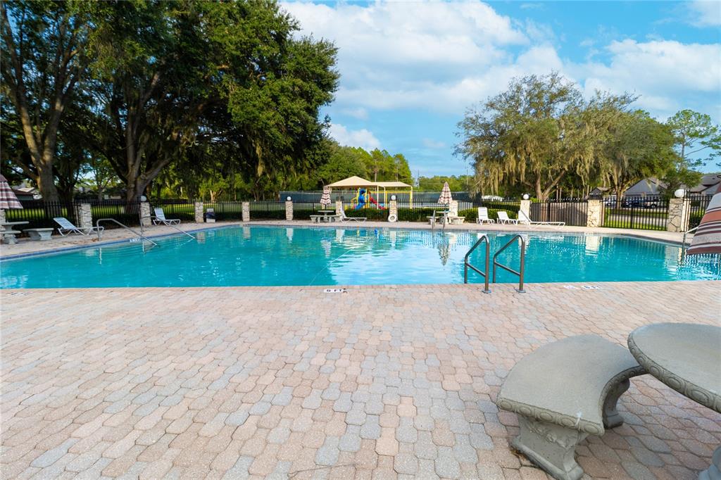 A swimming pool with a brick paver deck, lounge chairs, and a playground in the background — 3758 NW 56TH LANE, GAINESVILLE, FL