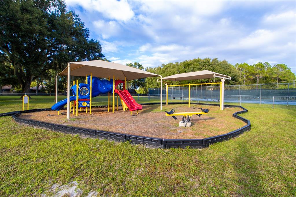A playground with a slide, swings, and a seesaw under shade structures in a park — 3758 NW 56TH LANE, GAINESVILLE, FL