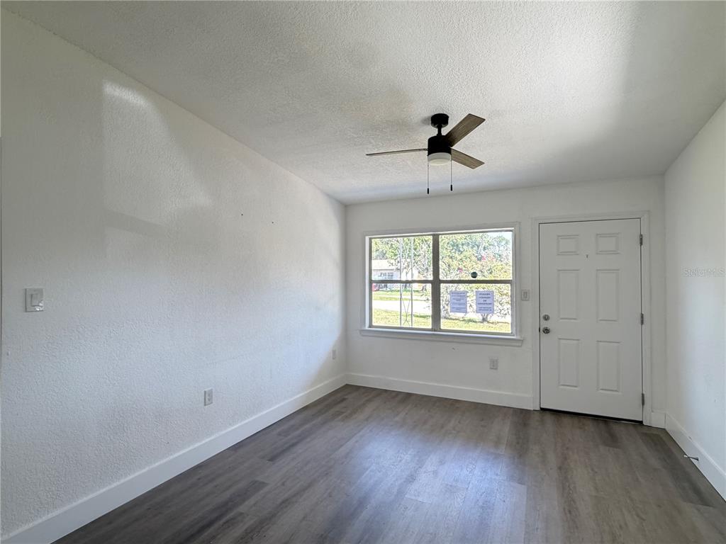An empty room with white walls, gray wood-look flooring, a ceiling fan, and a door — 3126 KELVINGTON DRIVE, ORLANDO, FL