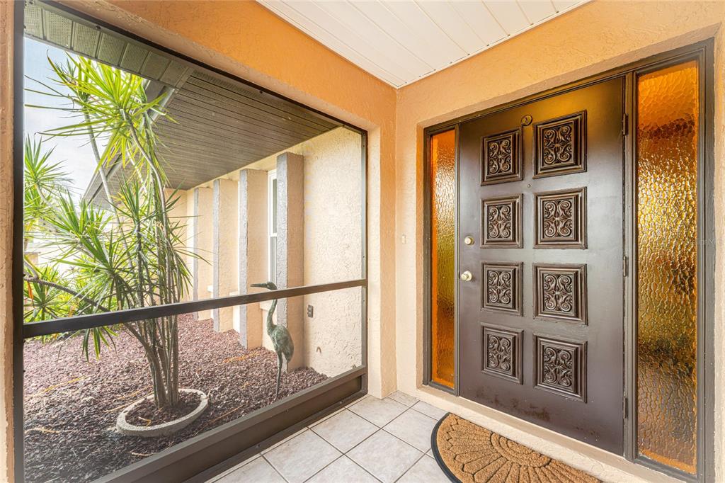 A covered entryway features a dark brown paneled front door with amber glass sidelights — 23278 MCNAMEE AVENUE, PORT CHARLOTTE, FL