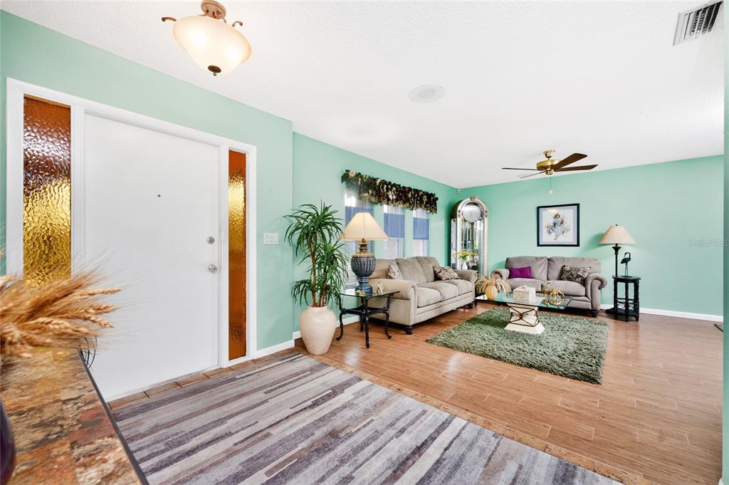 A living room features light green walls, wood-look tile flooring, and two beige sofas — 23278 MCNAMEE AVENUE, PORT CHARLOTTE, FL