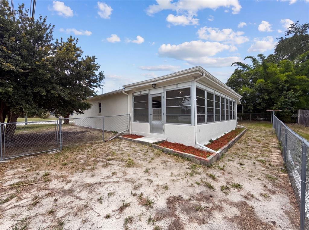 The exterior of a house features a screened-in porch and a chain-link fenced yard — 8053 EMBASSY BOULEVARD, PORT RICHEY, FL