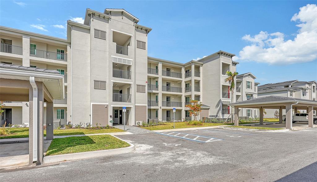 A multi-story apartment building with covered parking and a paved parking lot — 12280 WELLEN GOLF STREET UNIT 307, VENICE, FL