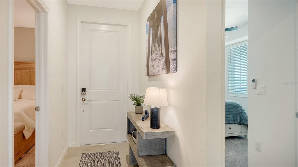 A hallway features a console table, a lamp, wall art, and doorways into two bedrooms — 12280 WELLEN GOLF STREET UNIT 307, VENICE, FL