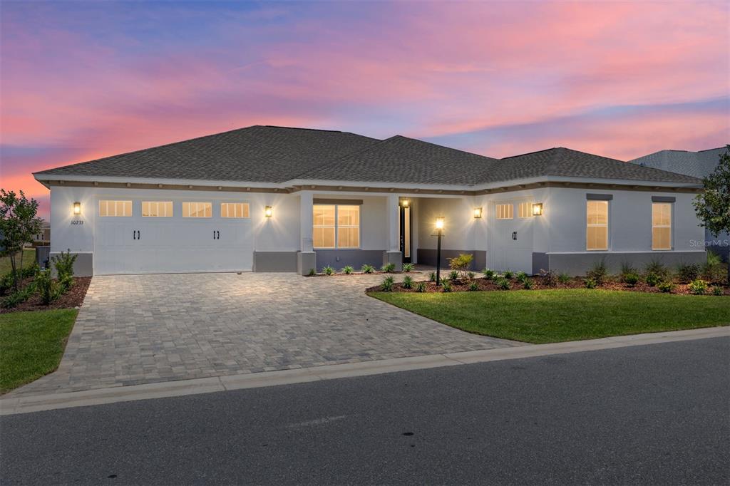 A single-story house with a white exterior, a paver driveway, and a three-car garage — 10233 SW 82ND PLACE ROAD, OCALA, FL