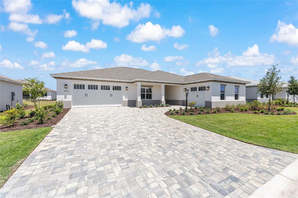 A single-story house with a paved driveway, two garages, and a light-colored stucco exterior — 10233 SW 82ND PLACE ROAD, OCALA, FL