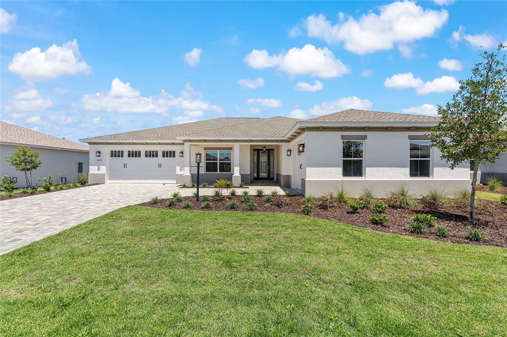 A single-story house with a white stucco exterior, a paved driveway, and a shingled roof — 10233 SW 82ND PLACE ROAD, OCALA, FL