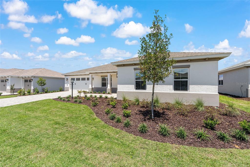 A single-story house with a light-colored stucco exterior, a paved driveway, and landscaped front yard — 10233 SW 82ND PLACE ROAD, OCALA, FL