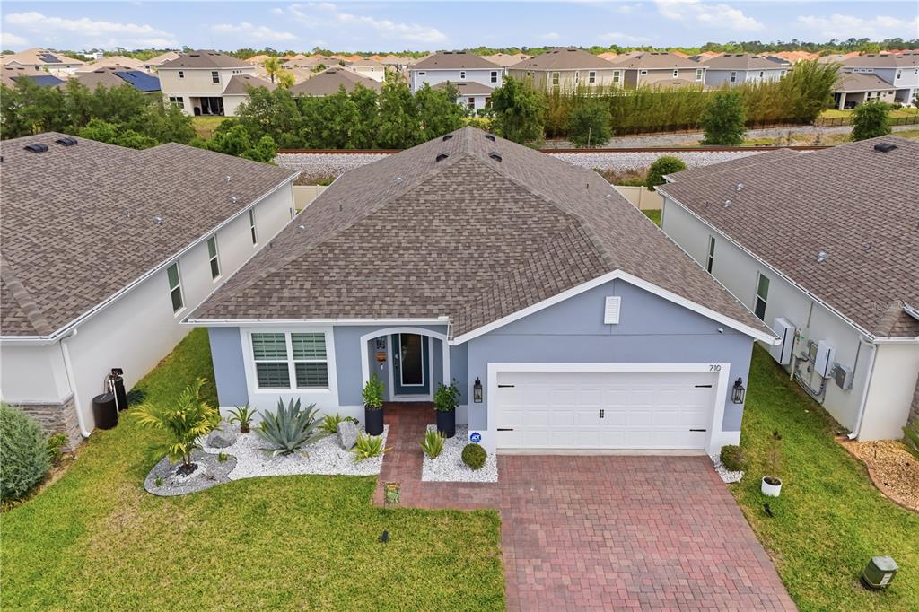 An aerial view of a single-story blue house with a paved driveway and landscaped yard — 710 CAMPO LANE, DAVENPORT, FL