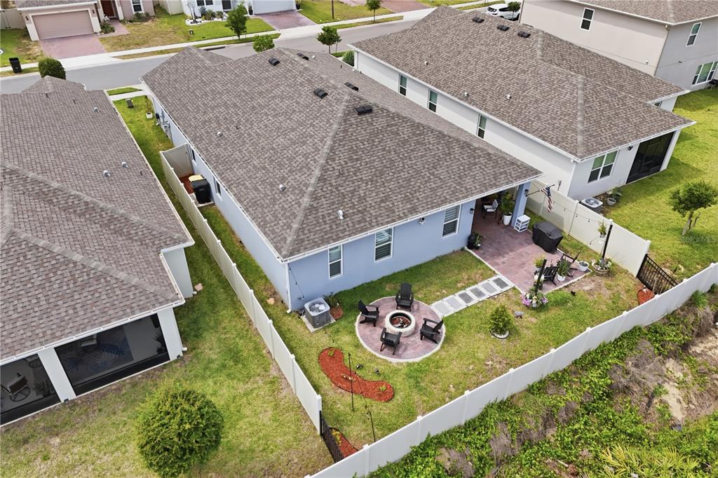 An aerial view of a backyard featuring a fire pit, patio, and white vinyl fencing — 710 CAMPO LANE, DAVENPORT, FL