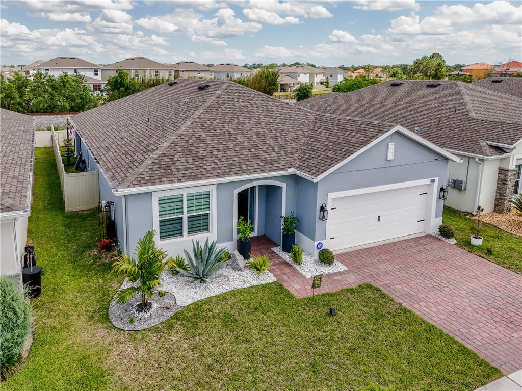 An aerial view of a blue single-story house with a brick driveway and landscaped yard — 710 CAMPO LANE, DAVENPORT, FL