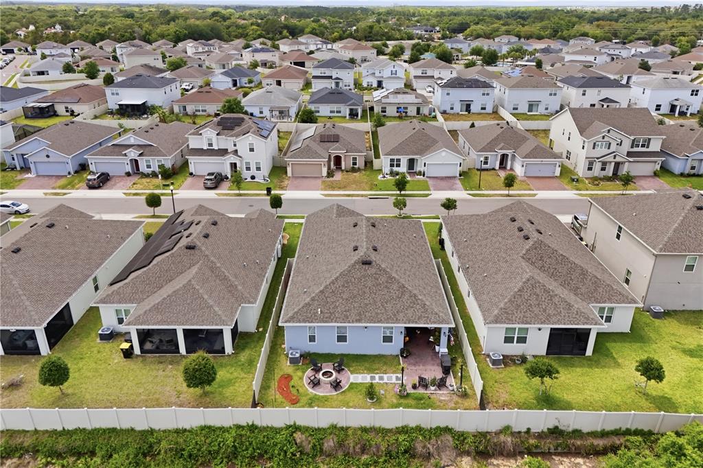 An aerial view shows the backyards and roofs of several suburban houses with fenced lots — 710 CAMPO LANE, DAVENPORT, FL