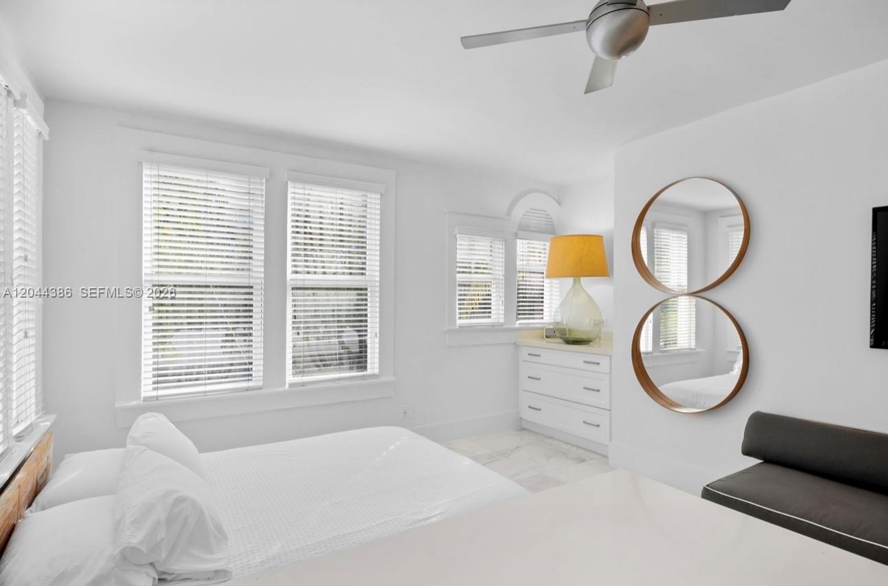 A bedroom features white walls, a ceiling fan, a white dresser, and a round mirror — 739 2nd St # 6, Miami Beach FL 33139, MIAMI BEACH, FL
