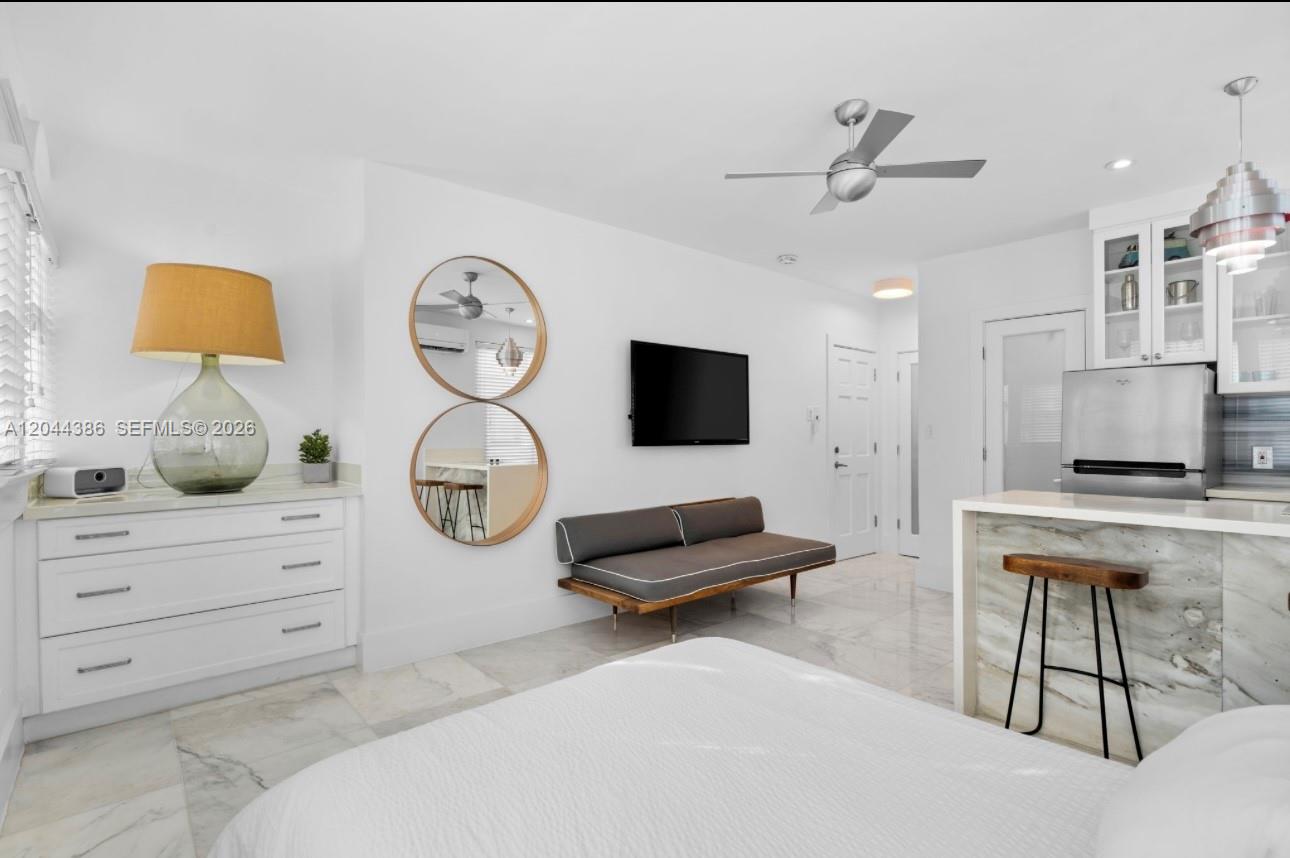 A modern studio apartment features a white dresser, a gray bench, and a kitchen island — 739 2nd St # 6, Miami Beach FL 33139, MIAMI BEACH, FL