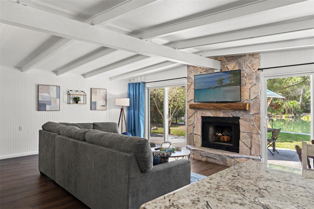 A living room features a stone fireplace, a gray sectional sofa, and sliding glass doors — 6053 PALM CREEK DRIVE, WEEKI WACHEE, FL