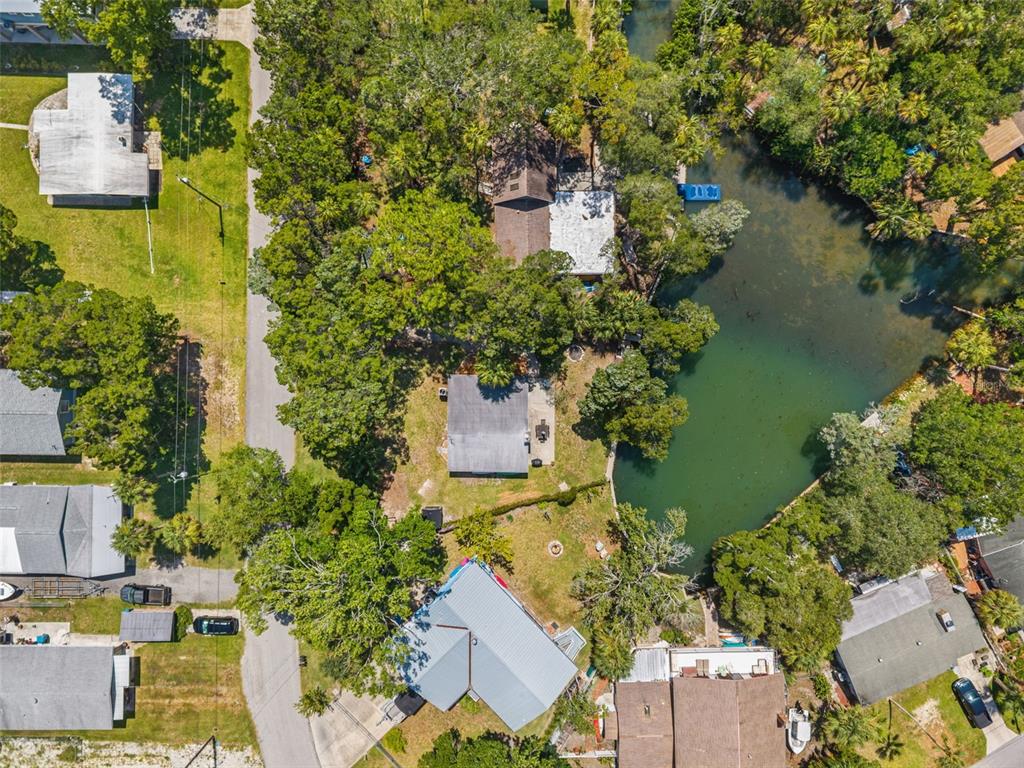 An aerial view shows several houses nestled among dense trees next to a small lake — 6053 PALM CREEK DRIVE, WEEKI WACHEE, FL