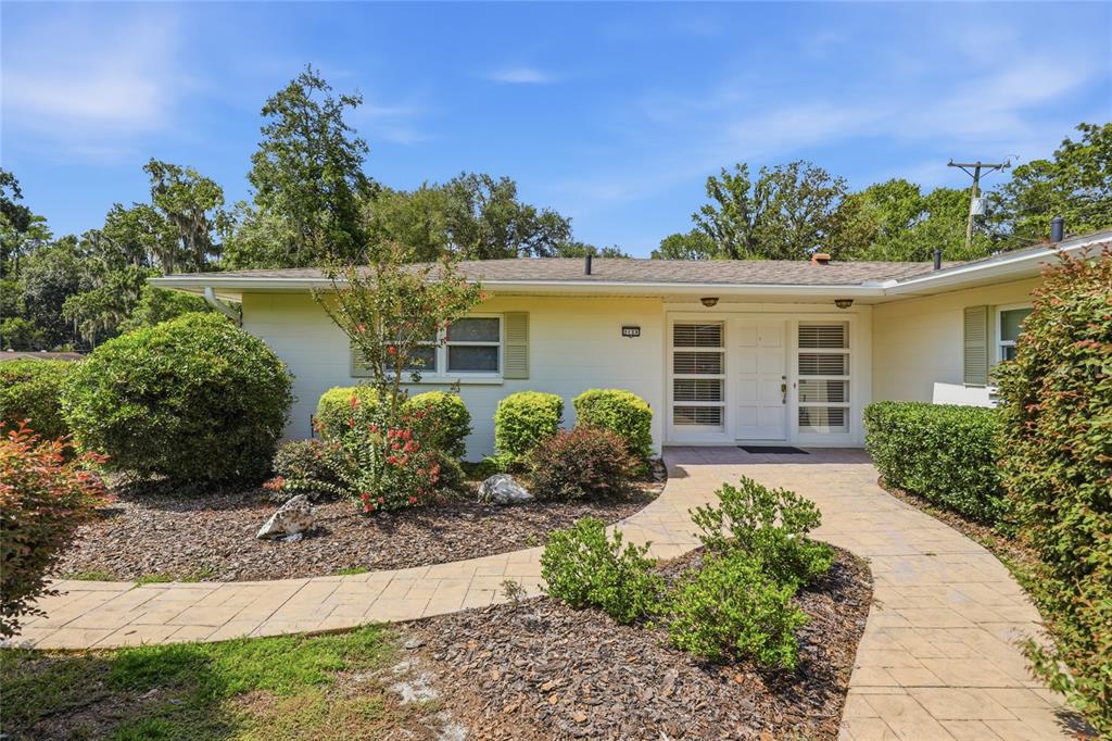 A single-story house with a light-colored exterior, a paved walkway, and manicured landscaping — 2138 NW 30TH PLACE, GAINESVILLE, FL