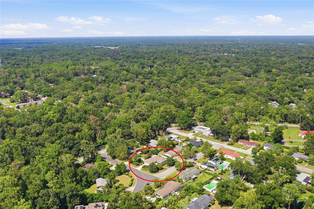 An aerial view shows a single-story house circled in a residential neighborhood surrounded by trees — 2138 NW 30TH PLACE, GAINESVILLE, FL