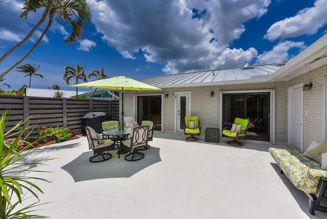 A spacious outdoor patio features a dining set with a lime green umbrella and seating — 1801 S Us Highway 1 # 1a, Jupiter FL 33477, JUPITER, FL