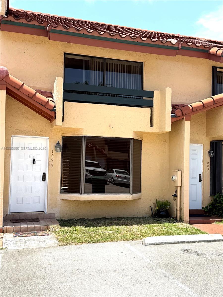 A two-story townhouse exterior features a bay window, a balcony, and a white front door — 10029 SW 77th Ct # 0, Miami FL 33156, MIAMI, FL