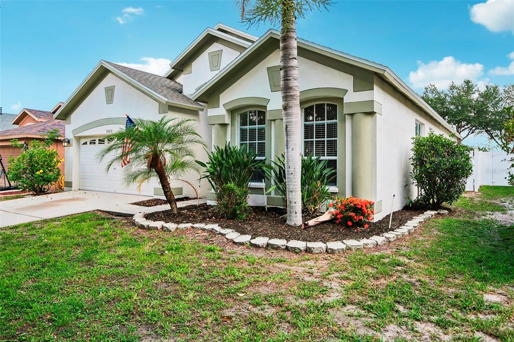 A single-story house with a white stucco exterior, a two-car garage, and a palm tree — 10616 LITTLE BEND LANE, RIVERVIEW, FL