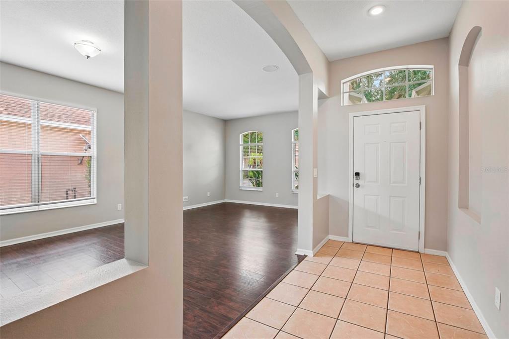 An entryway with tiled floors leads into a living area featuring dark wood-look flooring — 10616 LITTLE BEND LANE, RIVERVIEW, FL