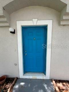 A bright blue front door is set within a white frame on a stucco exterior — 527 KILIMANJARO DRIVE, KISSIMMEE, FL