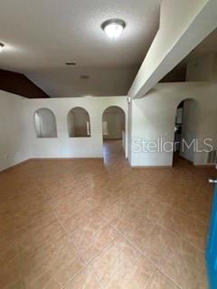 An interior room features light-colored tile flooring and three arched wall openings — 527 KILIMANJARO DRIVE, KISSIMMEE, FL