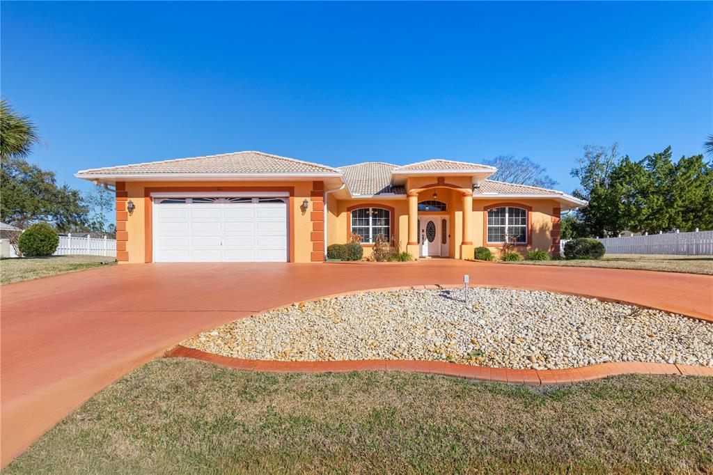 A single-story house with an orange stucco exterior, a two-car garage, and a paved driveway — 34 WOODFIELD DRIVE, PALM COAST, FL
