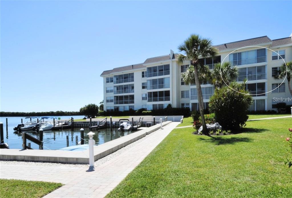 A multi-story waterfront apartment building with screened balconies and a private boat dock — 600 SUTTON PLACE UNIT B302, LONGBOAT KEY, FL