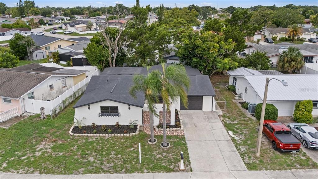 An aerial view of a single-story house with a dark roof, palm trees, and driveway — 9401 GLEN MOOR LANE, PORT RICHEY, FL