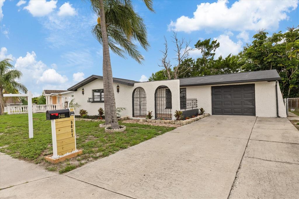 A single-story house with a white stucco exterior, arched entryways, and a concrete driveway — 9401 GLEN MOOR LANE, PORT RICHEY, FL