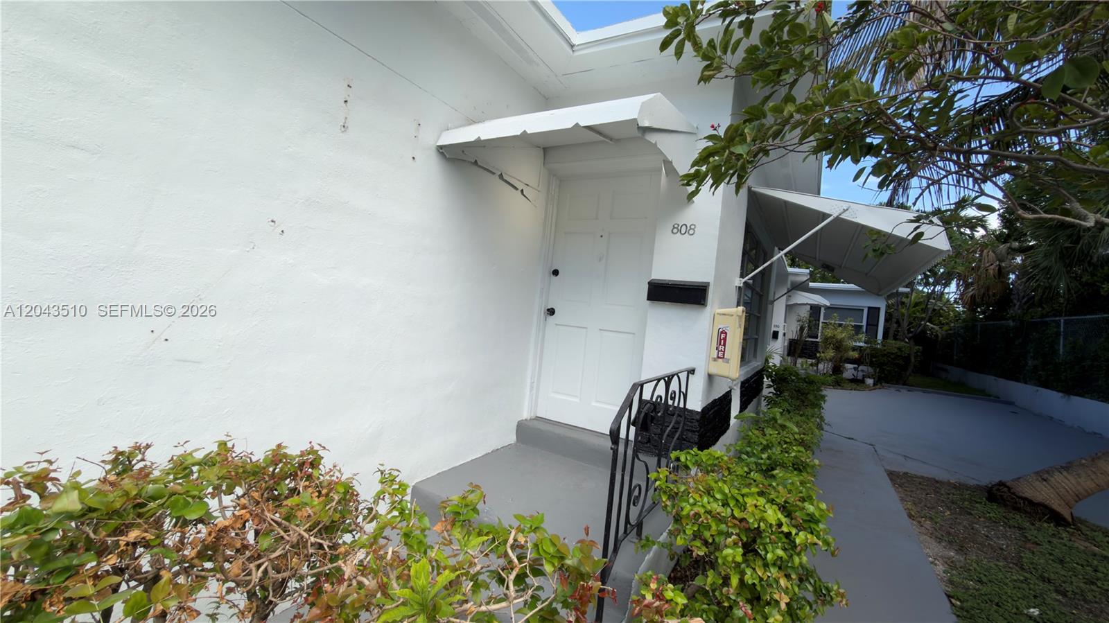 A white exterior wall with a front door, metal awning, and a fire extinguisher box — 808 84th St # 808, Miami Beach FL 33141, MIAMI BEACH, FL