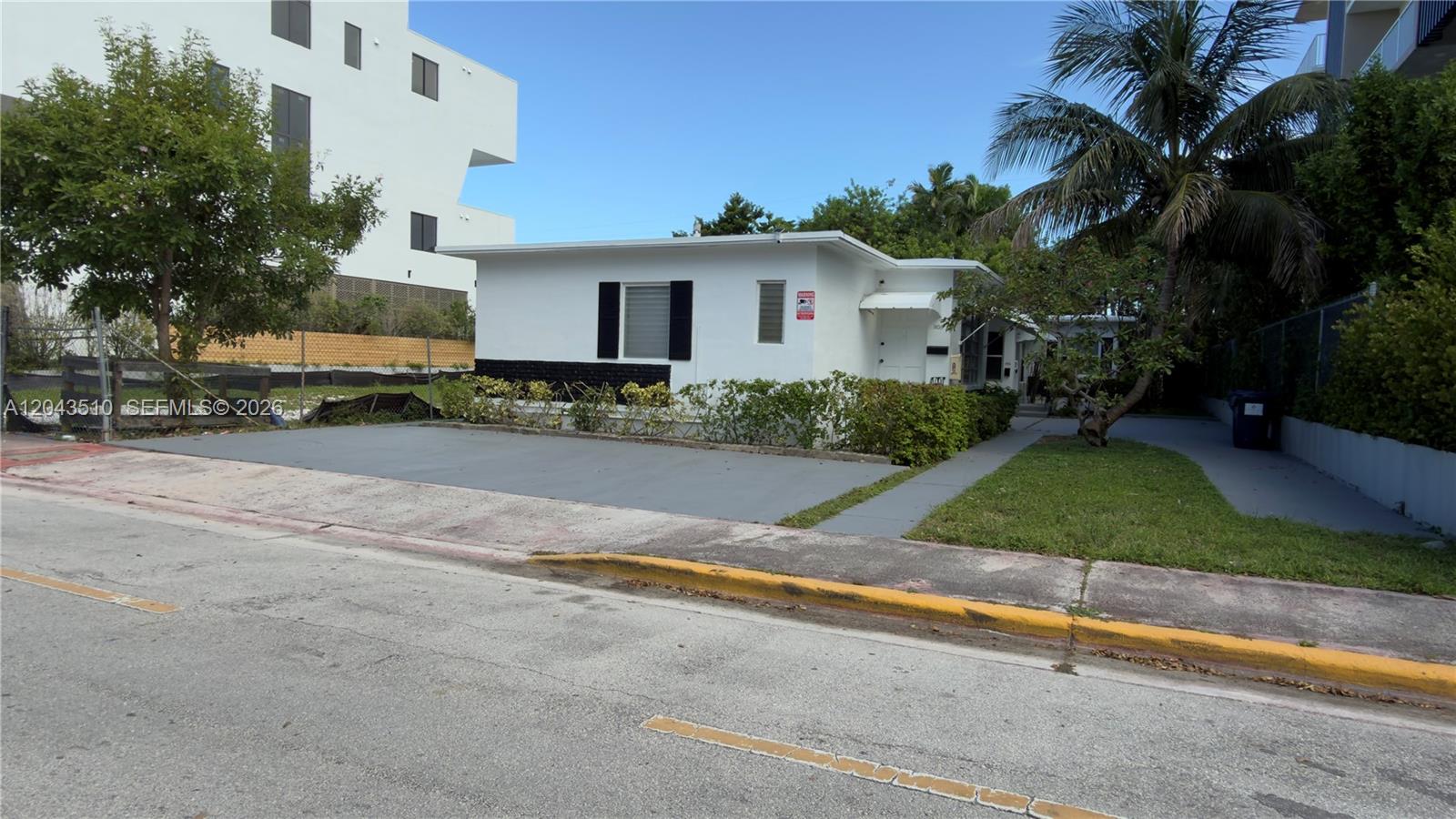 A white single-story house features a gray driveway, black shutters, and a palm tree — 808 84th St # 808, Miami Beach FL 33141, MIAMI BEACH, FL