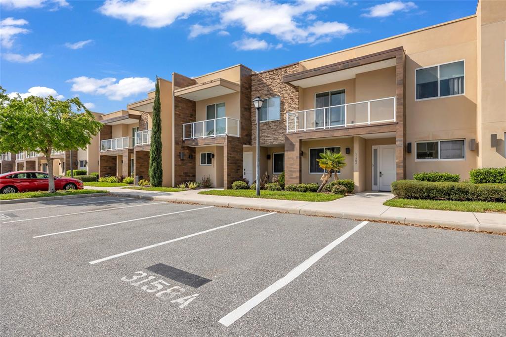 A multi-story apartment building with balconies and a parking lot in the foreground — 3158 BRASILIA AVENUE, KISSIMMEE, FL