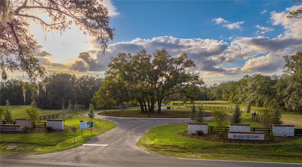 An entrance to a residential community features a circular driveway, stone pillars, and large trees — 17287 SW 11 COURT, NEWBERRY, FL